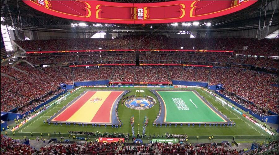 Spanish and Saudi Arabian flags are held across a football pitch before Spain versus Saudi Arabia.